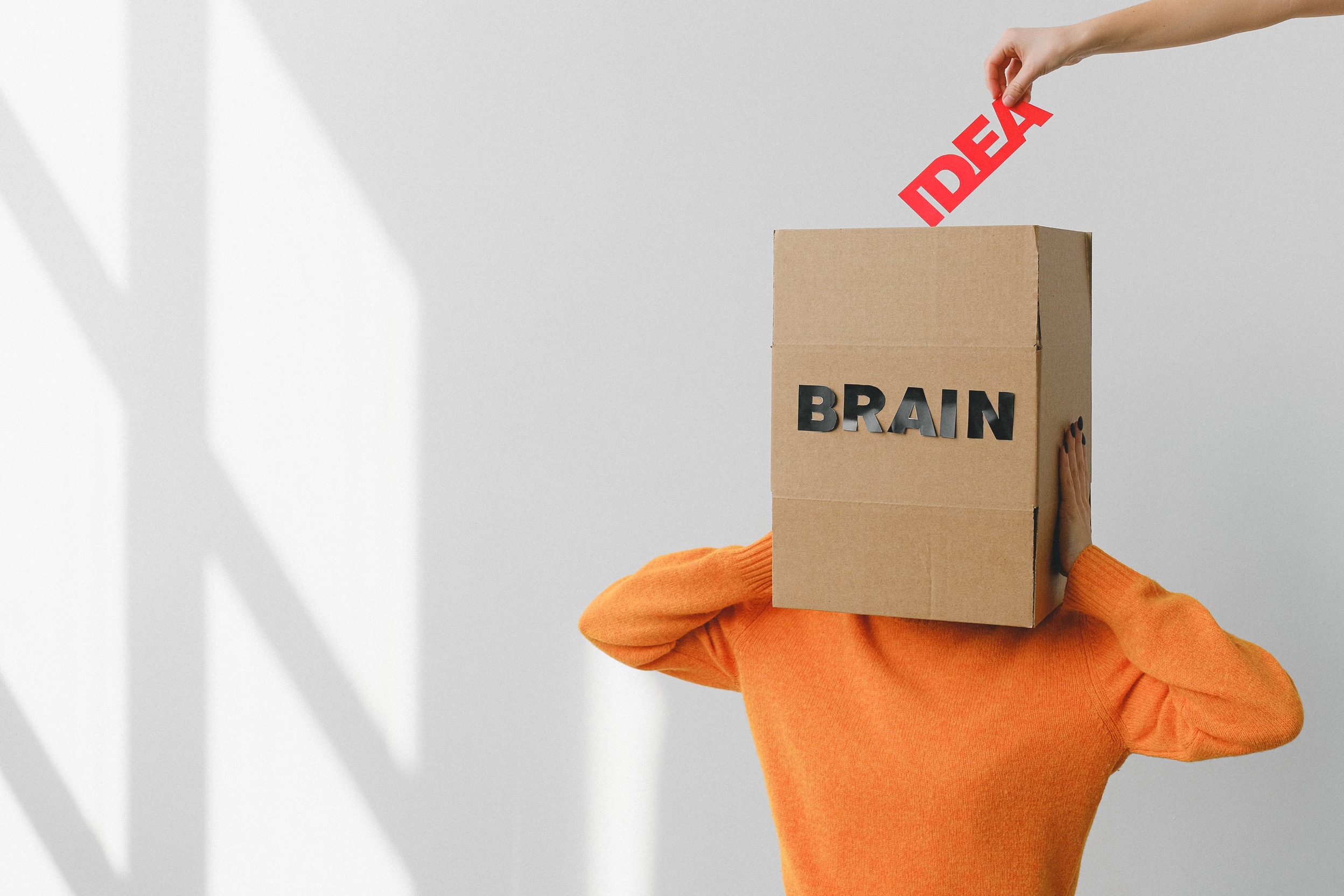 Person with a box labeled as brain and idea being poured into it
